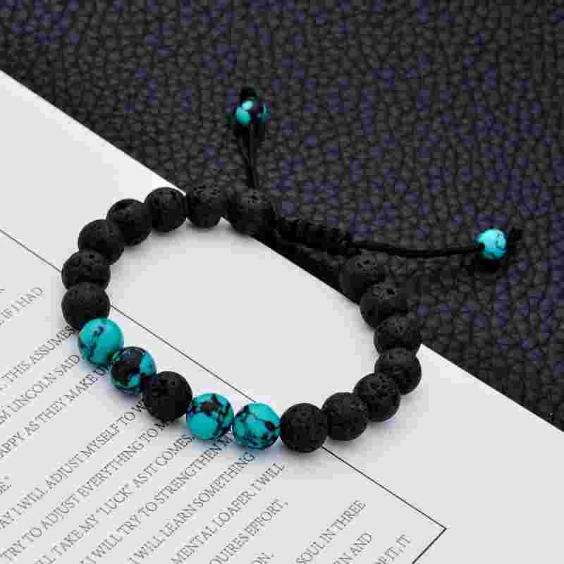 Turquoise and black volcanic stone bracelet worn on wrist, featuring round beads and adjustable black cord for a casual look