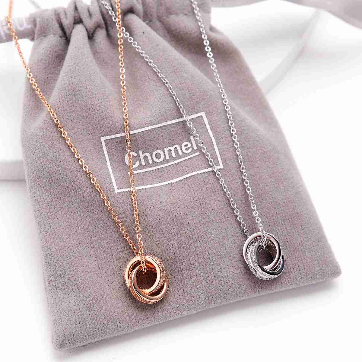 Silver and rose gold-tone double ring necklaces with circular pendant design, displayed on a soft gray Chomel branded pouch