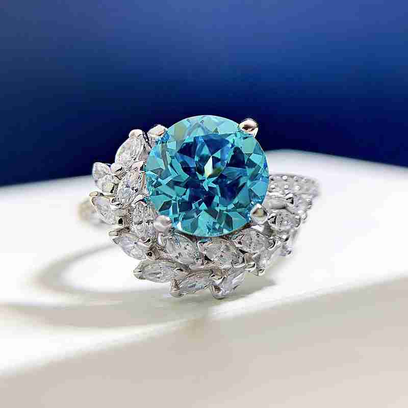 Silver ring with a vibrant round blue rhinestone center stone and a surrounding halo of marquise-shaped clear rhinestones, sophisticated jewelry