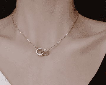 Close-up of silver double ring necklace on a woman's neck, featuring intertwined rings with sparkling stones, stylish jewelry