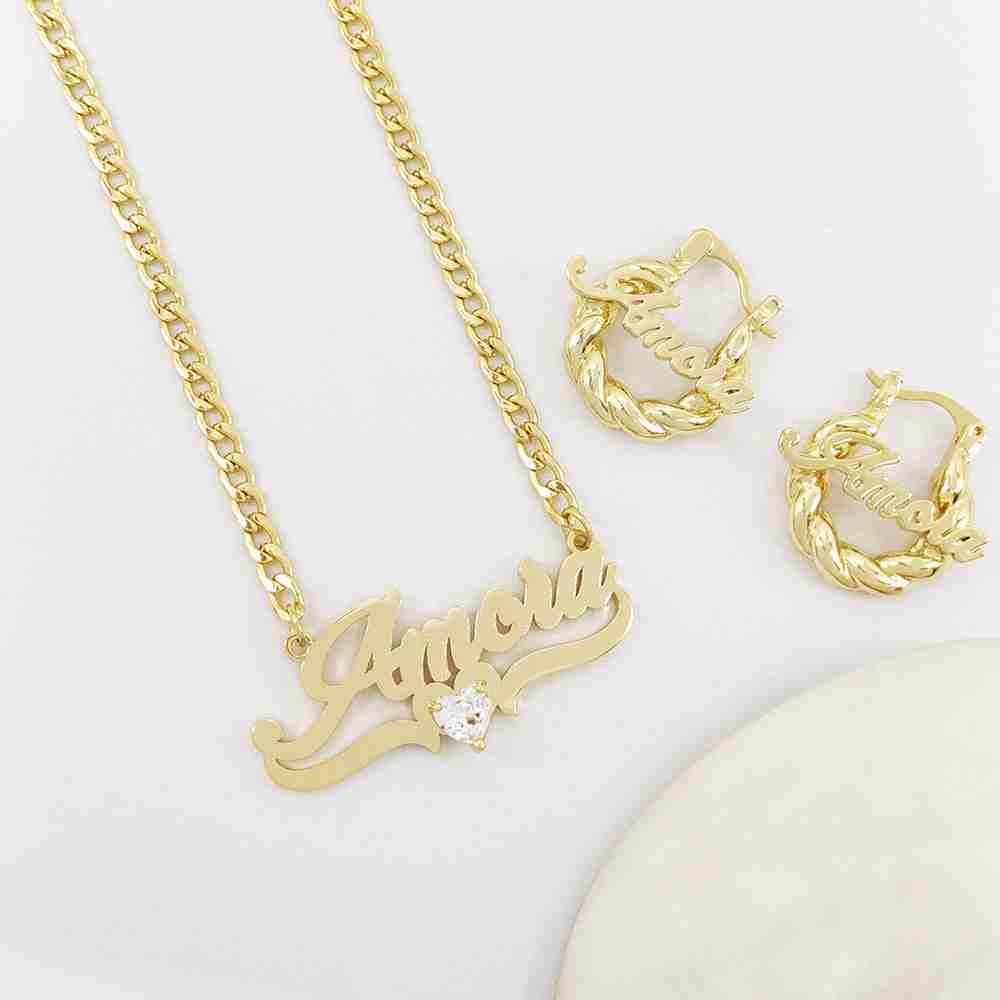 Gold personalized name necklace with heart-shaped birthstone, matching gold hoop earrings, and chain on a white background